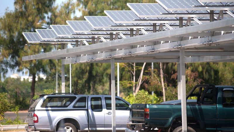 Zwei Autos stehen auf einem Parkplatz unter Photovoltaigdächern 